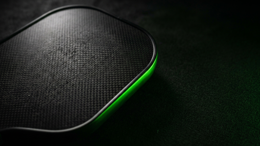 Close-up of a black carbon-fiber pickleball paddle face showing the grit texture that wears out over time